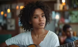 an african american girl playing guitar at home