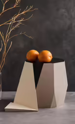two oranges are on top of a gray object