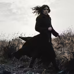 a woman with long hair running across a field