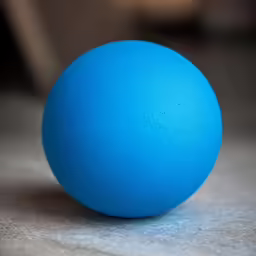 a bright blue ball of foam on a concrete surface