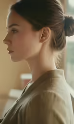 a woman with a bun updo standing next to a window