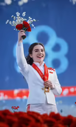 a woman in uniform smiles and holds flowers