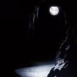 an image of a night at the dark cave with the moon in the sky