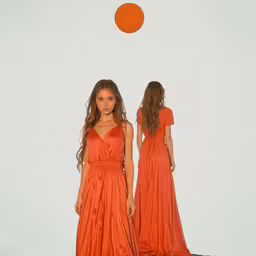 two women in red dresses watching an orange ball