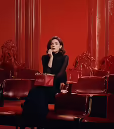 woman wearing black and red dress sitting on a red chair