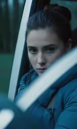a girl sits in a car wearing a blue coat