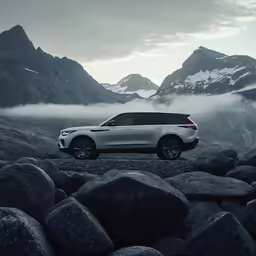 the land rover parked on the rocks near the mountains