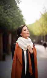 a woman is standing on a street with her scarf over her shoulders