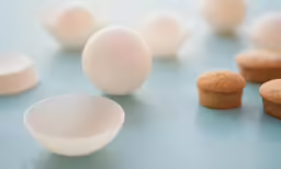 a counter with some white and brown cookies near a egg
