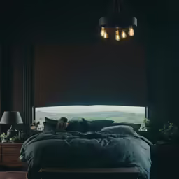 a man laying in bed looking out of the window