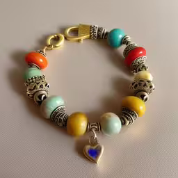 the colorful bracelet has a blue heart on it,a colorful bracelet has a heart charm on it
