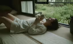 a woman lying on her back holding a coffee cup