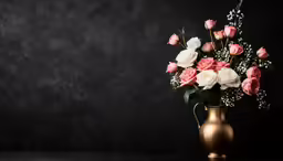 a gold vase with flowers in it sitting on a table