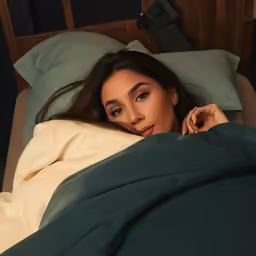 a young girl laying in bed with her hand on her chin