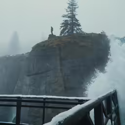 a wooden rail that is near a large waterfall