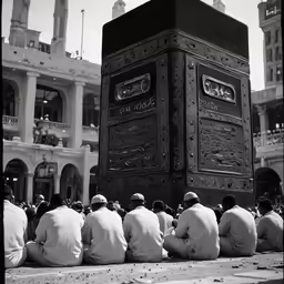 four men are sitting in front of an elaborate square statue