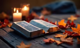 some silver bars laying on some leaves next to some candles