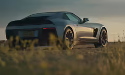 the front end of a silver sports car on a dirt road