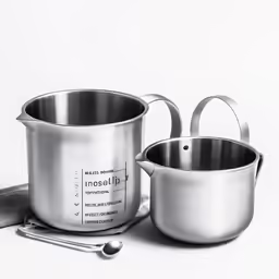 two pots and a measuring tape sitting on a table