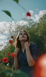 a woman standing on the grass holding her hands together