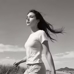 an asian woman in white shirt running in grassy area