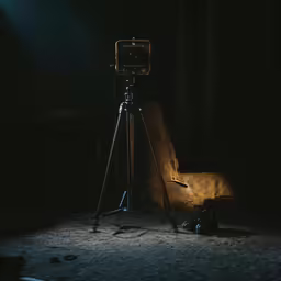 an old tripod in the dark with a camera sitting on it
