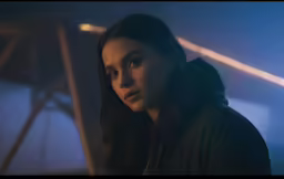 a woman wearing a jacket stares into the distance