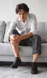 a young man sitting on a couch wearing socks