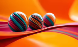 three colorful balls are set on a wavy surface