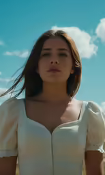 a woman is standing under a blue sky with clouds