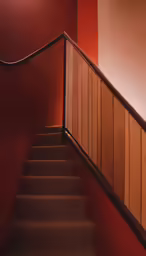 stairs and railing in a stairwell area with a red wall