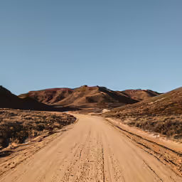 a gravel road leading into the distance in front of some mountains
