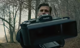 a man in the woods holding a camera