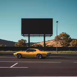 a yellow car parked in a parking lot under a billboard