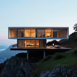 two building sitting on the top of a cliff near water