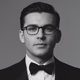 a man in glasses and a tuxedo with a bow tie