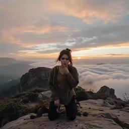 a woman is sitting on top of a cliff