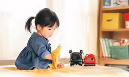 small child sitting on a bed playing with an item
