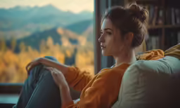 an image of a woman sitting on the couch looking out the window