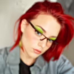 a woman with red hair and glasses has bright green eye shadows