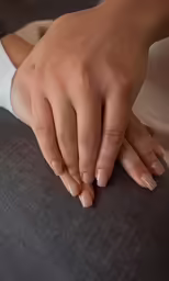 a female hand with white fingernails is sitting on a chair