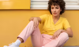 a woman in yellow shirt sitting on the sidewalk