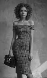 a woman posing in a dress holding a purse and posing for the camera