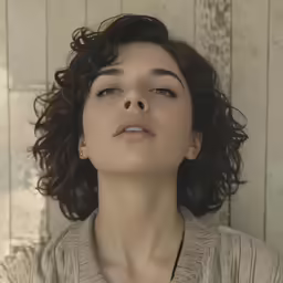 a woman with curly hair is staring at something