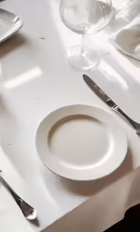 a white plate with a knife, fork and spoon on a table