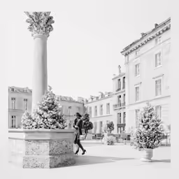 a black and white photo of a statue and two men walking in the distance