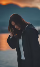 a woman wearing a jacket standing next to the water