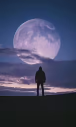 a man stands on a hilltop looking out to the sky at night, with a large moon visible above him