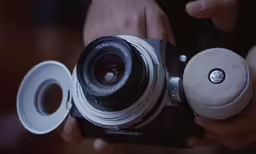this is a person holding an old camera with the lens removed