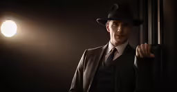 man in suit and hat, standing against wall with lights